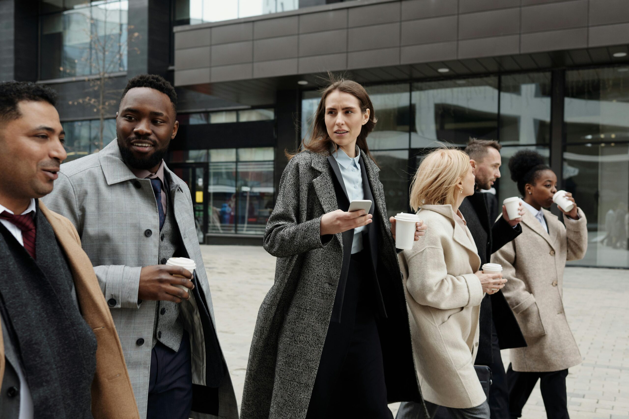 Professional men and women walking downtown drinking their coffee